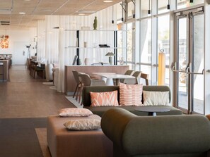 A modern interior with a seating area, a dining space, and a reception desk.