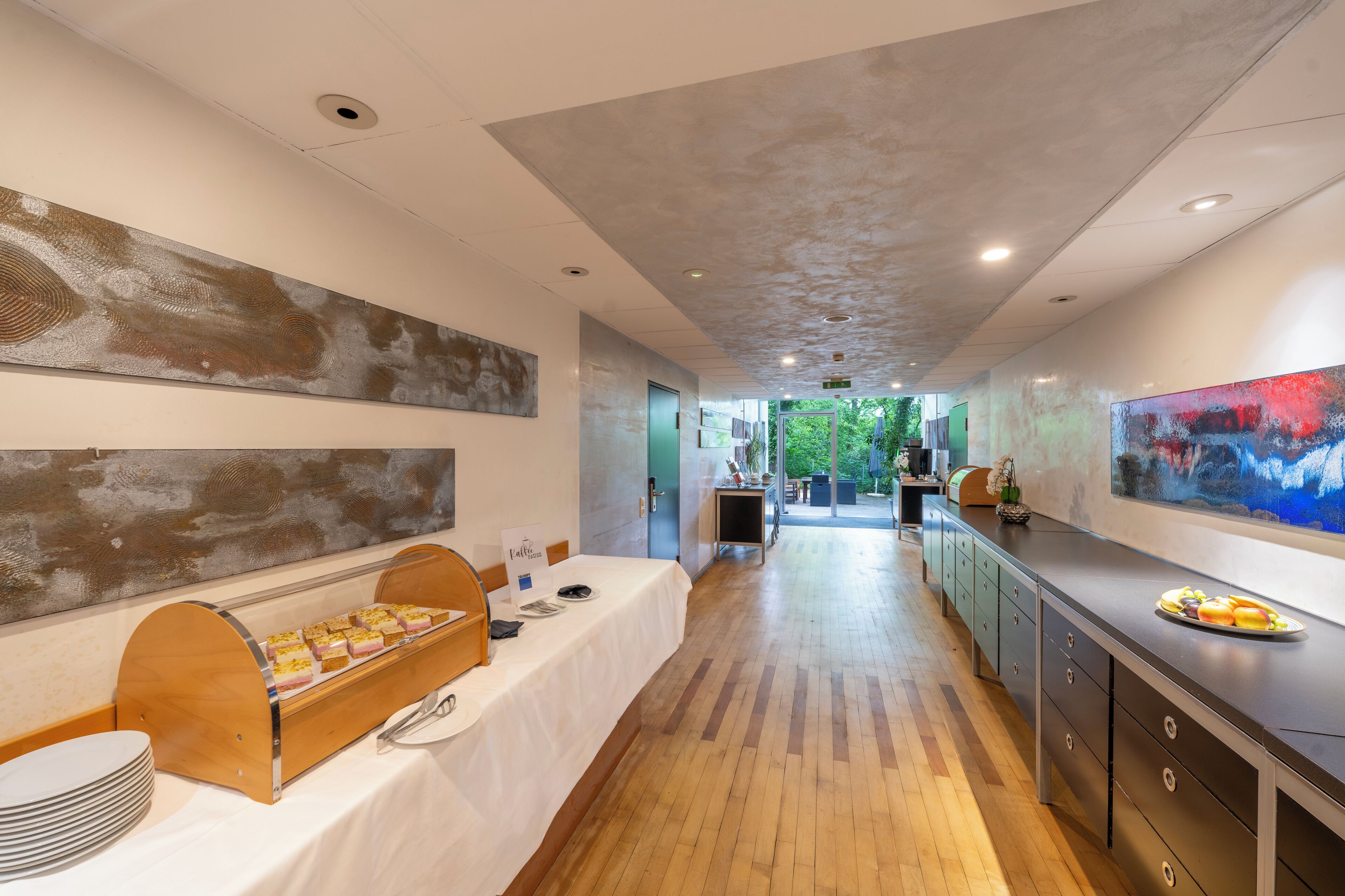 A hotel corridor with a buffet table, a reception area, and a view of the outdoors.