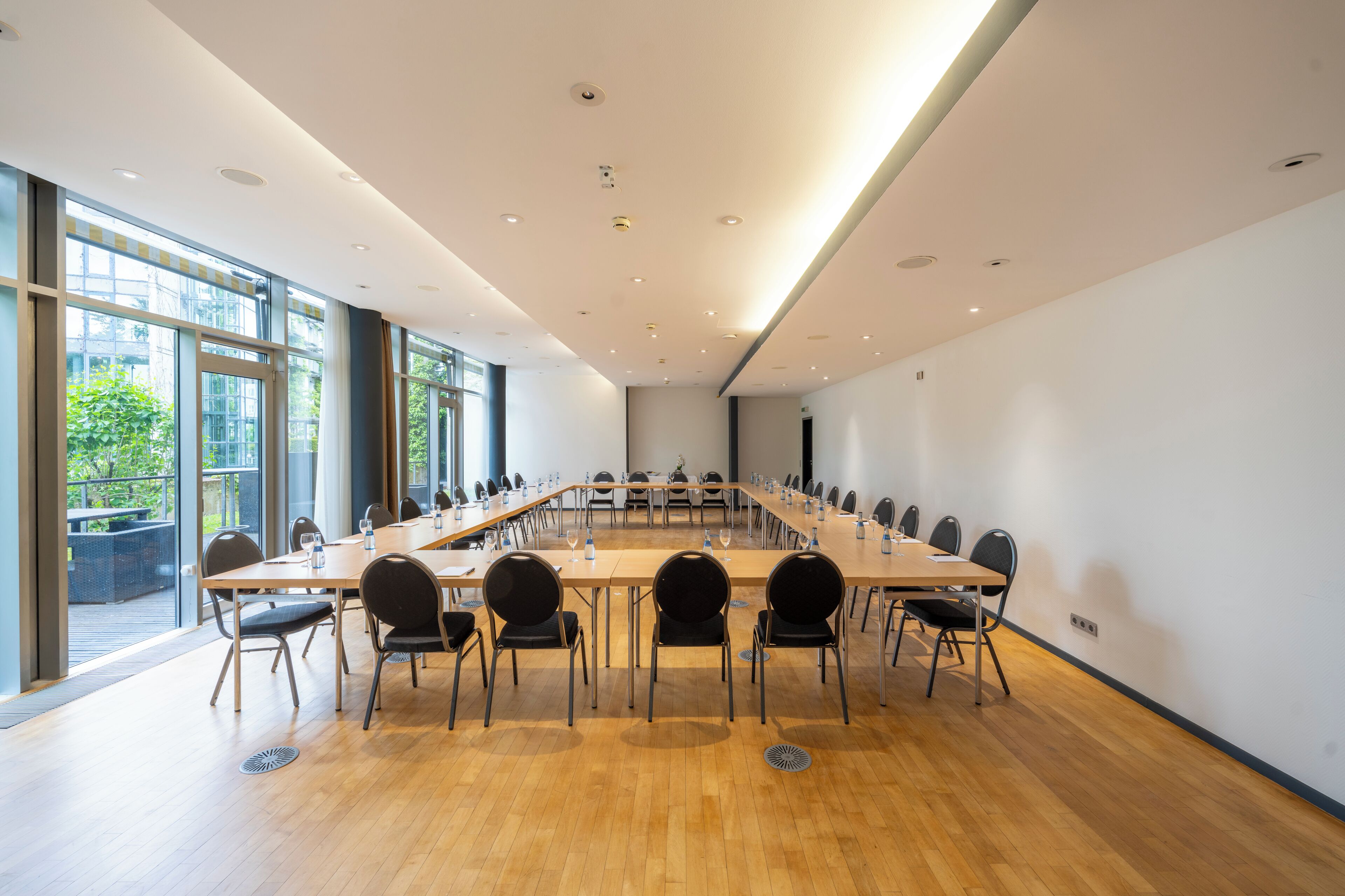 A conference room with a long table, chairs, and a view through large windows.