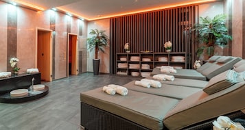 Un moderno spa con tres camillas de masaje, una zona de recepción y un estante en la pared con toallas.