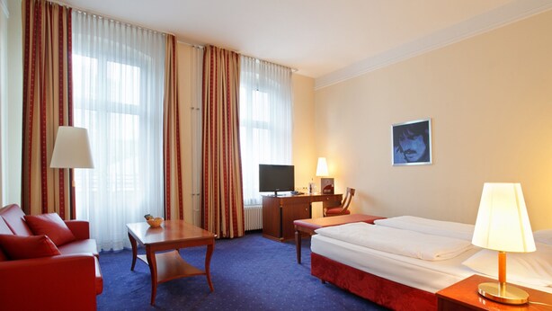 A hotel room with a bed, a desk, a chair, a television, and a lamp. - acom Hotel Berlin Kurfürstendamm (Berlin)