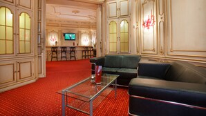A spacious living room with a red carpet, a glass coffee table, a black leather sofa, and a television in the background. - acom Hotel Berlin Kurfürstendamm (Berlin)