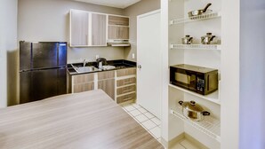 A compact kitchen with a refrigerator, microwave, and built-in cabinets.
