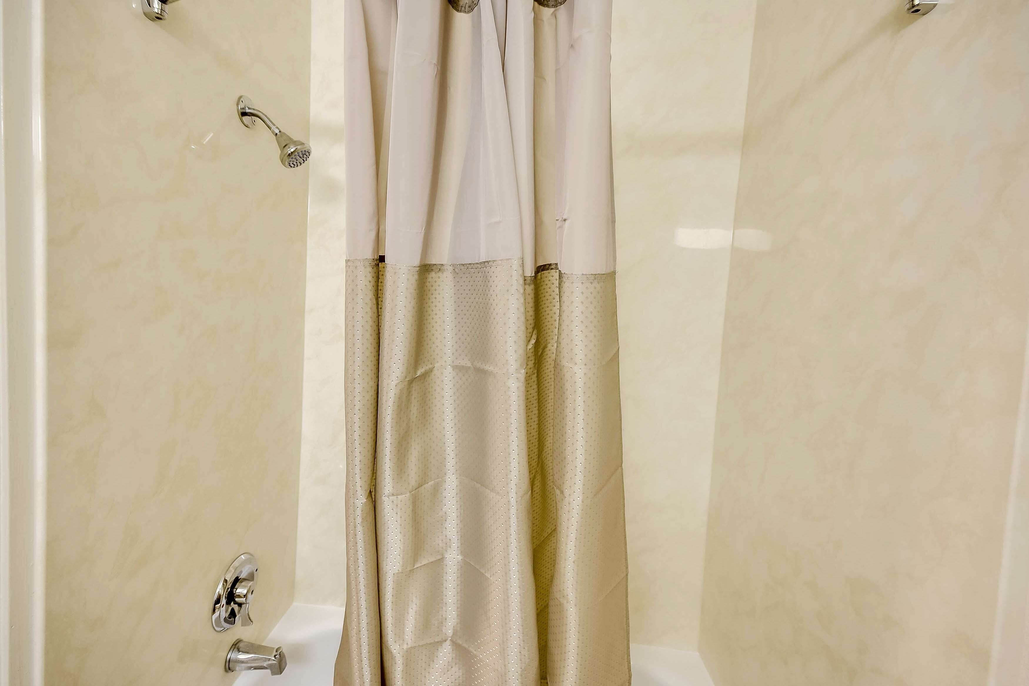 A bathroom with a shower curtain, a bathtub, and a faucet.