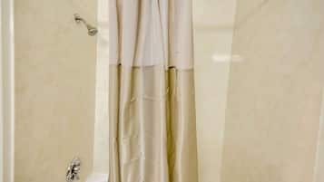 Un baño con cortina de ducha, bañera y grifo.