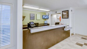 A reception area with a reception desk, a mounted television, and a 'Welcome Home!' sign.