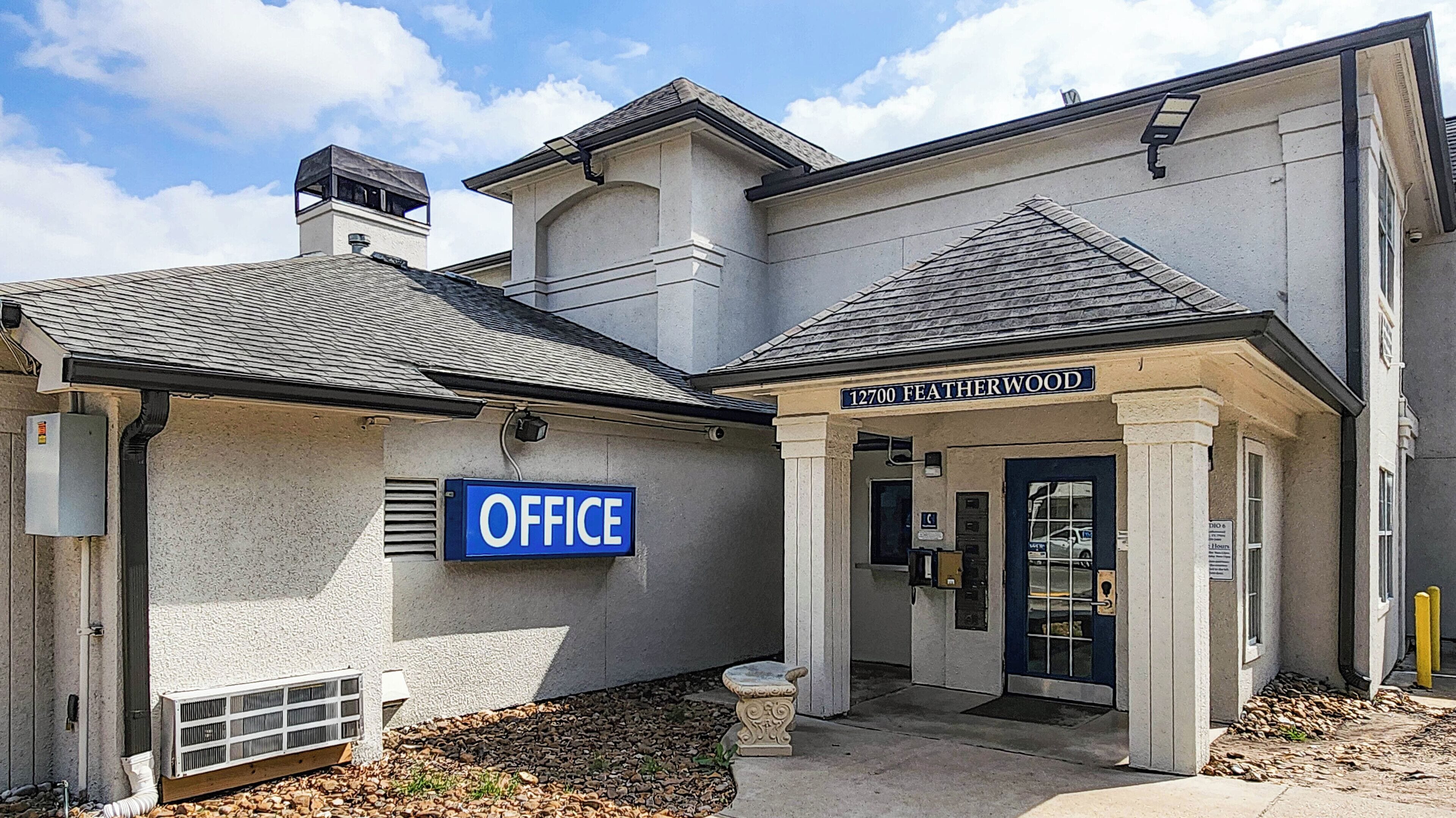 A building with a sign reading "OFFICE" and another sign above the entrance that says "12700 FEATHERWOOD".