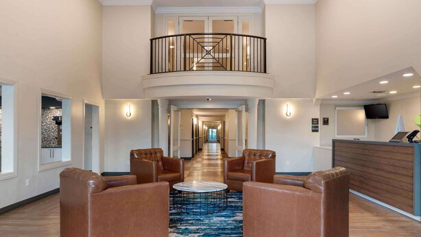 A spacious lobby with leather armchairs, a central coffee table, and a staircase leading to an upper level.