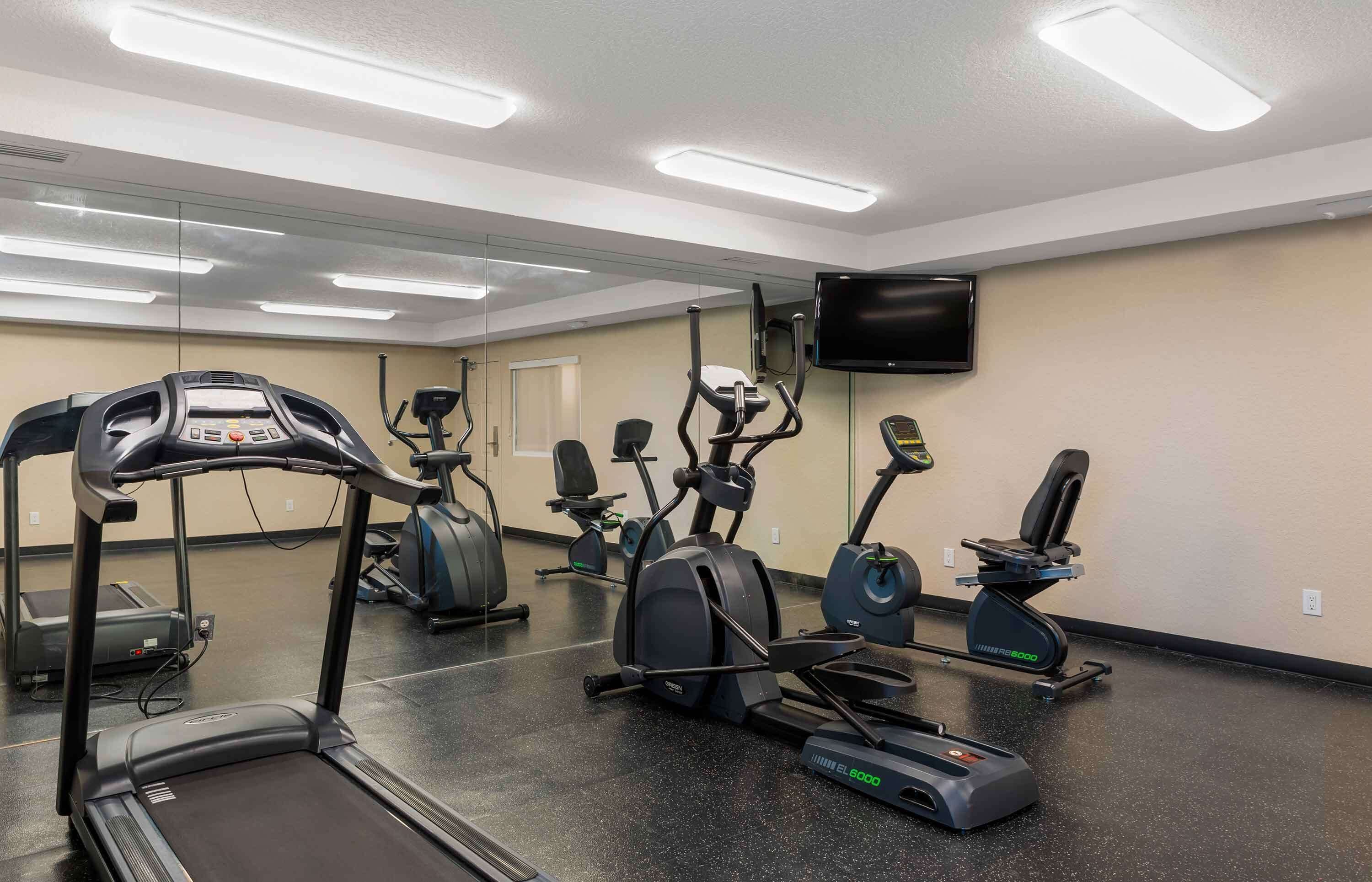 Une salle de sport équipée de tapis de course, de vélos elliptiques et d’un vélo d’appartement.