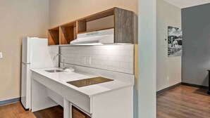 A compact kitchen with white cabinetry, a built-in oven, and a sink.