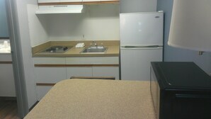 A compact kitchenette with a sink, a stove, and a refrigerator. - HomeTowne Studios by Red Roof Chantilly (Chantilly)