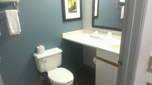 A small bathroom with a toilet, sink, and mirror. - HomeTowne Studios by Red Roof Chantilly (Chantilly)