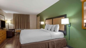 Una habitación de hotel con una cama grande, un escritorio, una silla, un aparador y una televisión.