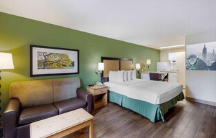 A hotel room with a bed, a desk, a chair, a couch, and a small table.
