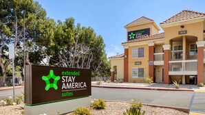 A sign for Extended Stay America Suites with a building in the background.