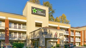 Un hotel de varios pisos con cartel de Extended Stay America, entrada al vestíbulo y zona de estacionamiento.