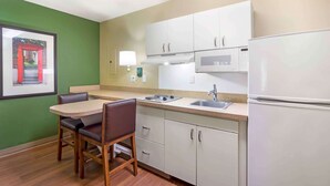 Una cocina compacta con comedor, que incluye microondas, estufa, lavabo y refrigerador.