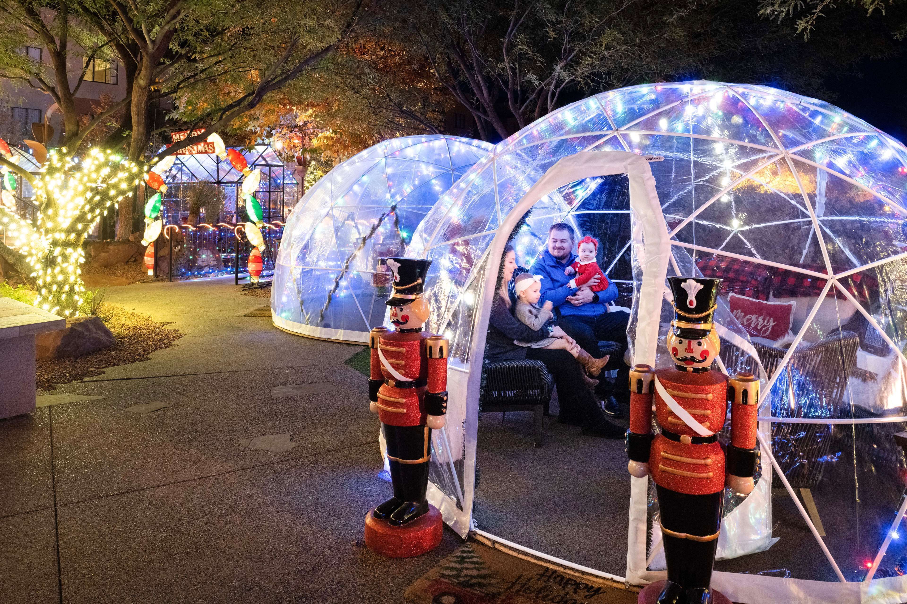A transparent dome structure with a person inside, surrounded by festive lights and nutcracker statues.