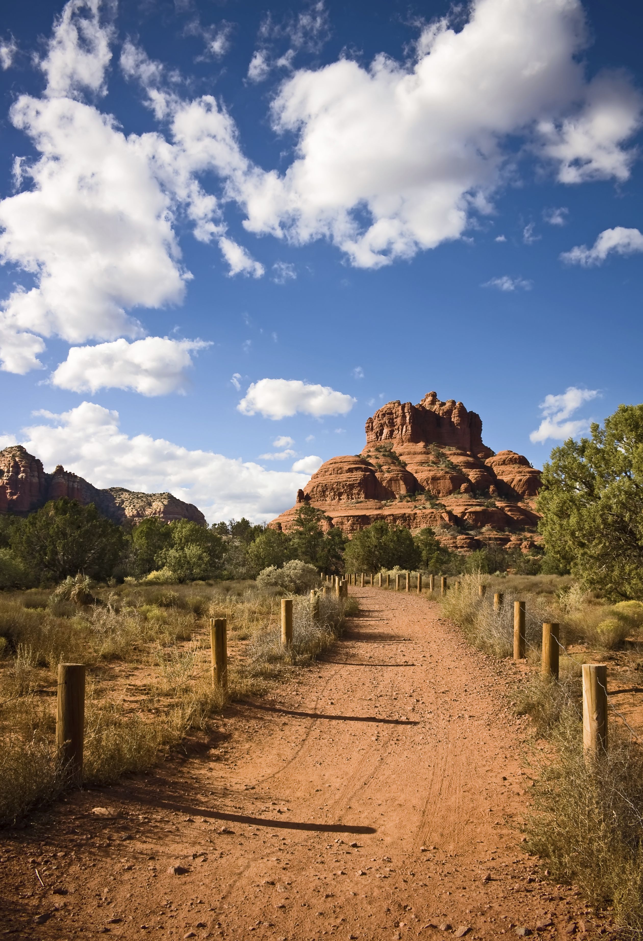 A dirt path leading to a rocky hill with sparse vegetation.