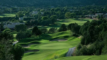 A golf course with rolling green hills, sand bunkers, and a winding path.