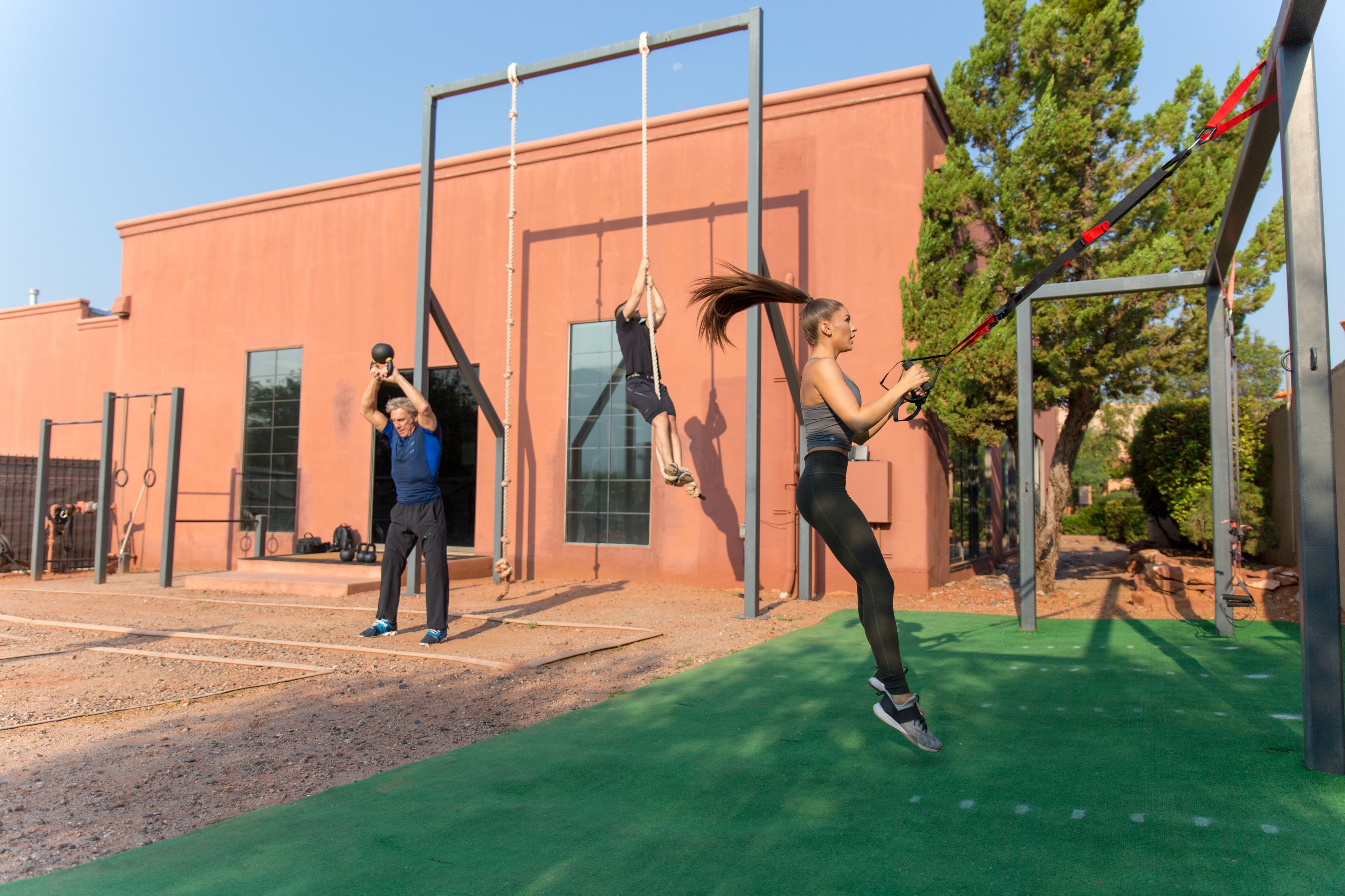 An outdoor gym with exercise equipment, a building in the background, and a clear sky.