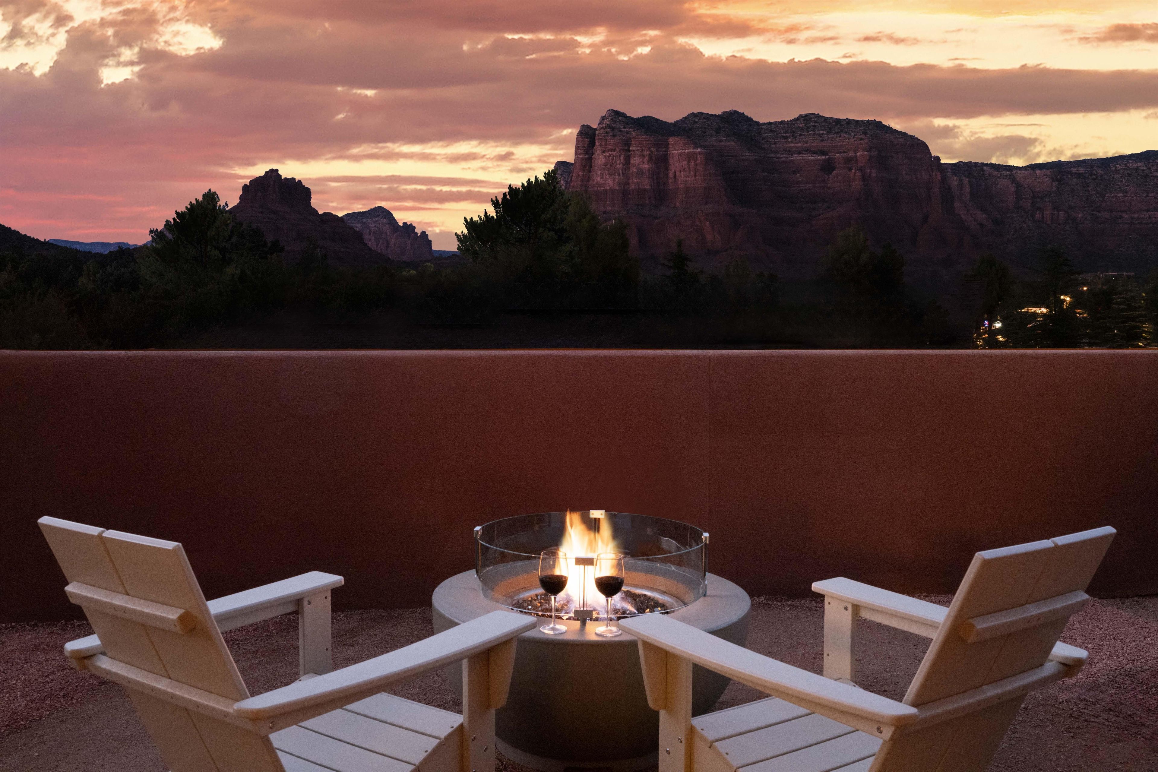 Un patio con un pozo de fuego y dos sillas que dan a un paisaje montañoso.