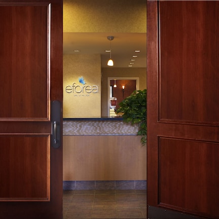 A hotel reception area with a wooden reception desk, a sign reading "eforea SPA AT MILTON", and a potted plant.