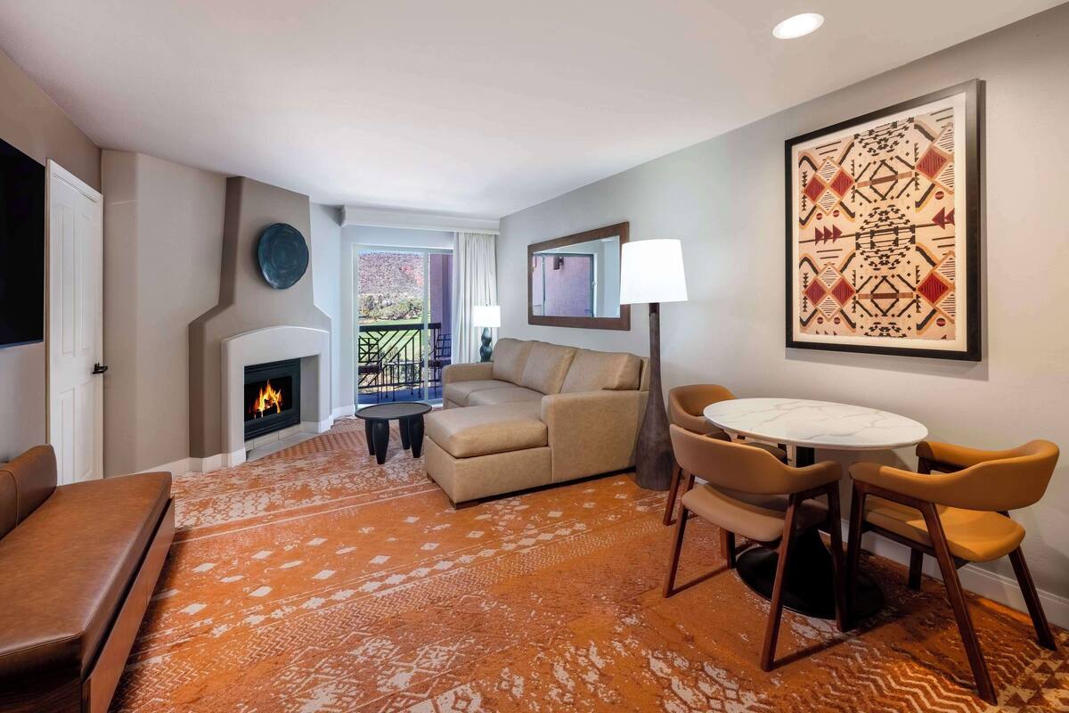 A living room with a fireplace, a sofa, a coffee table, and a dining area with chairs.