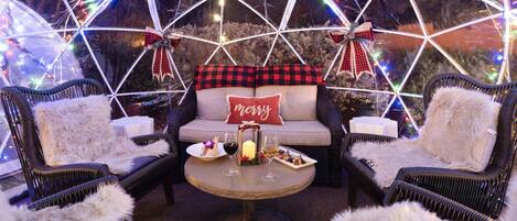 A cozy seating area with wicker chairs, a round table, and a couch adorned with festive decorations.