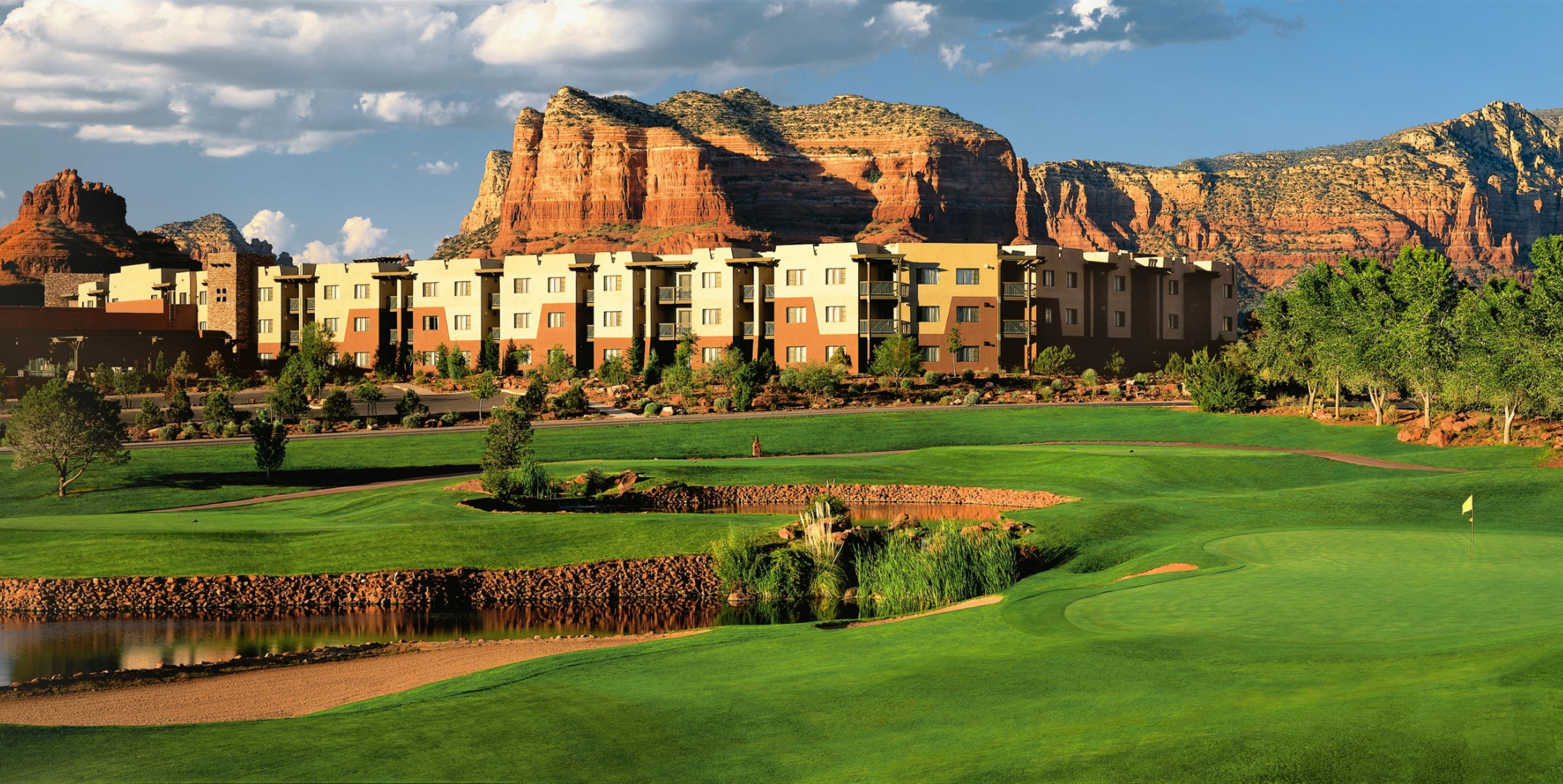 A golf course with a pond, surrounded by a residential area with multi-story buildings.