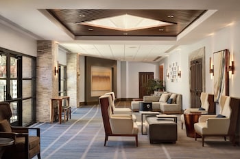 A hotel room with a large bed, a bathroom with a bathtub, a TV, and a view of a canyon. at Hilton Sedona Resort at Bell Rock