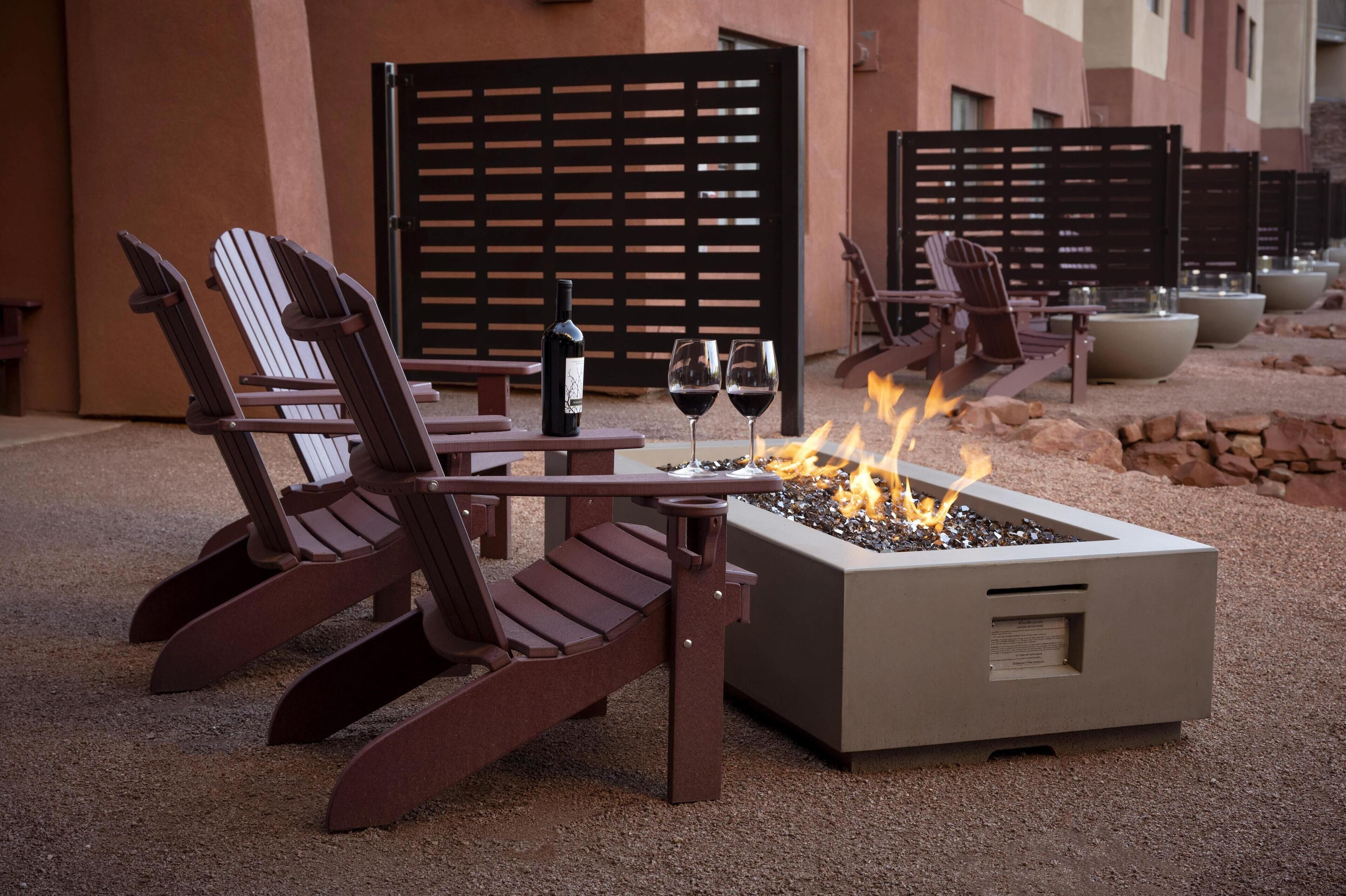 Una chimenea con dos sillones, una mesa, una botella de vino y dos copas.