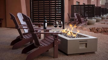 Una chimenea con dos sillones, una mesa, una botella de vino y dos copas.