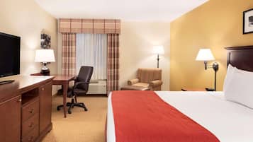 A hotel room with a bed, a desk, a chair, a television, and two lamps.