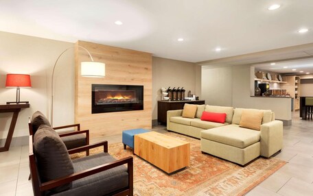 A modern living room with a fireplace, a sofa set, a coffee table, and a dining area in the background.