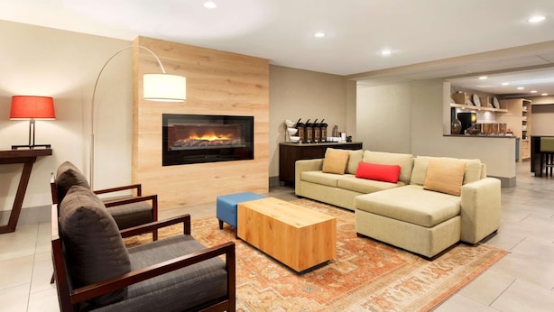 A modern living room with a fireplace, a sofa set, a coffee table, and a dining area in the background.