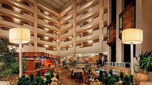 A multi-level hotel lobby with a central atrium, multiple floors, and a variety of seating areas.