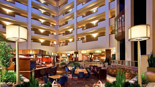 A multi-level hotel lobby with a central seating area, multiple floors, and a variety of amenities including a bar and dining space.