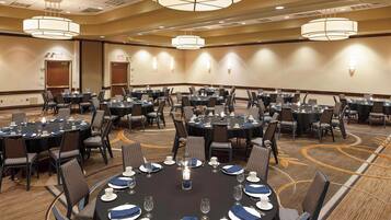 A conference room with multiple round tables, each set with plates, glasses, and chairs.