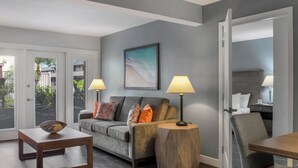 A modern living room with a grey sofa, two side tables with lamps, a wooden coffee table, and a painting on the wall.