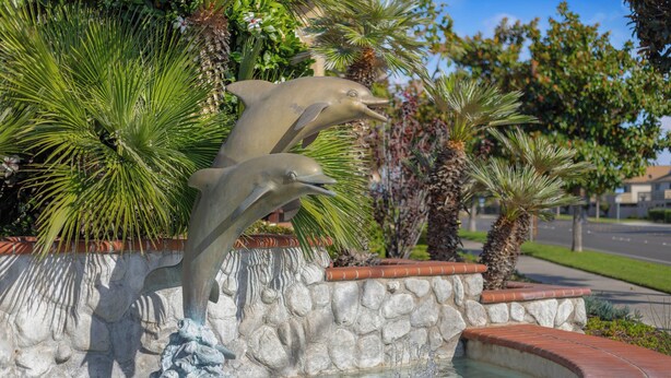 A fountain with two dolphin sculptures and a stone wall.