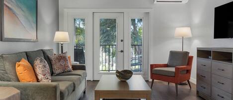 A modern living room with a sofa, armchair, coffee table, and a TV.