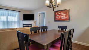 A dining area with a wooden table and chairs, a sofa, and a flat-screen TV above a fireplace. - Bluegreen Vacations Suites at Hershey, an Ascend Collection Resort (Hershey)