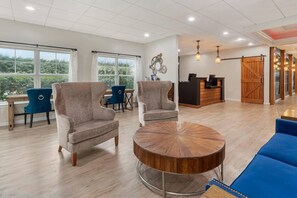 A spacious room with a reception desk, seating area with armchairs and a round coffee table, and large windows offering a view of greenery. - Bluegreen Vacations Suites at Hershey, an Ascend Collection Resort (Hershey)