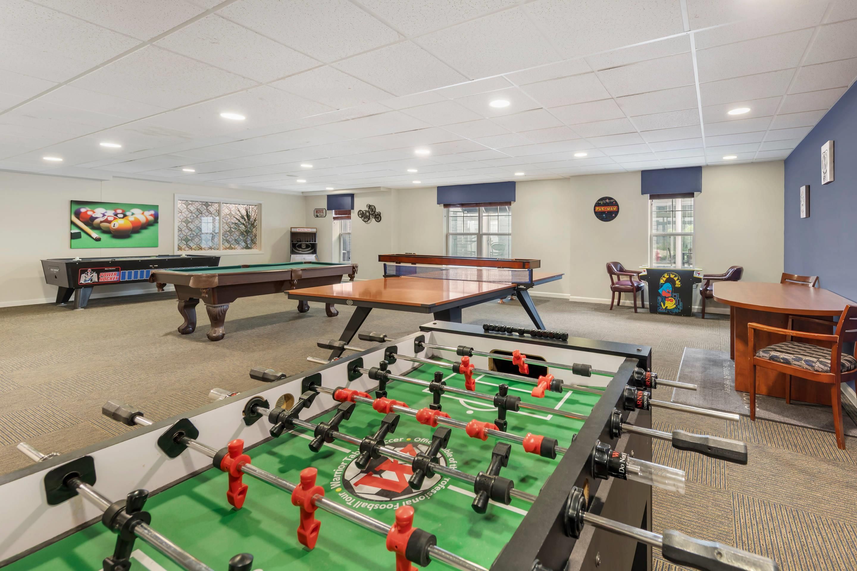 A recreational room with a foosball table, pool table, and billiards table.
