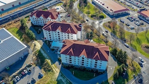 Ett hotell med flera våningar och ett rött tak, omgivet av parkeringsplatser och vägar.