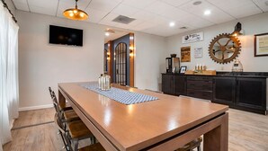 Una cocina moderna con una mesa de madera, taburetes de bar y una máquina de café.