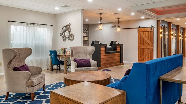 A modern hotel lobby with a reception desk, seating area, and a large clock on the wall. - Bluegreen Vacations Suites at Hershey, an Ascend Collection Resort (Hershey)