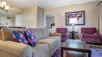 Un salon comprenant un canapé, deux fauteuils, une table basse et un tableau encadré accroché au mur.
