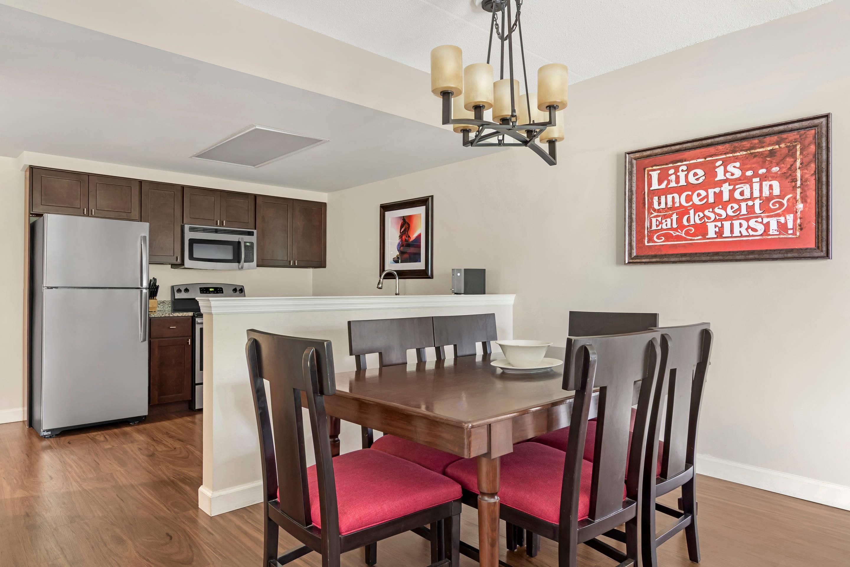 A modern kitchen with a built-in microwave, stainless steel refrigerator, and wooden cabinets.